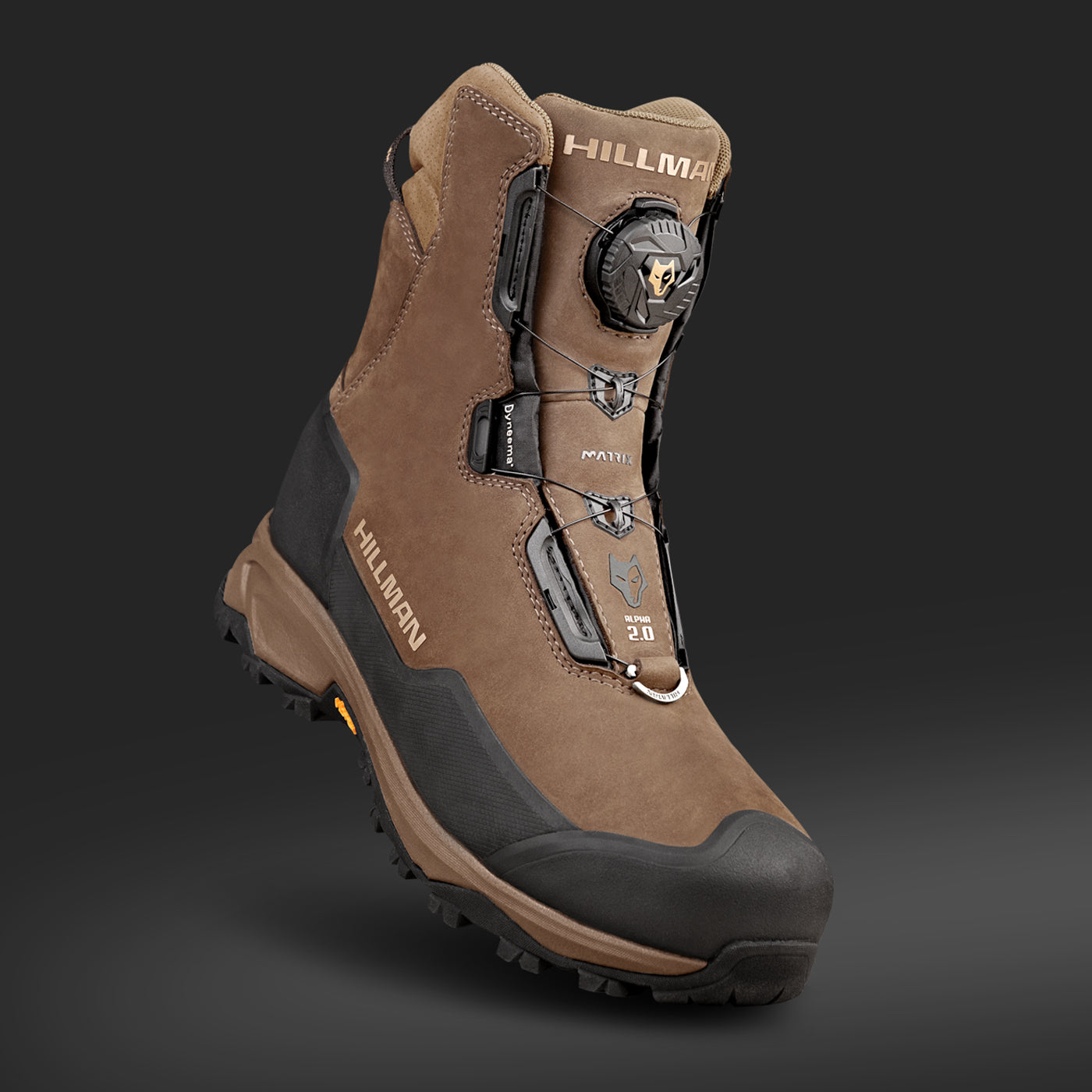 Brown hiking boot with black accents and textured sole on a gray background. Features include a knob lacing system and HILLMAN branding on the sides and tongue. Suitable for rugged terrain.