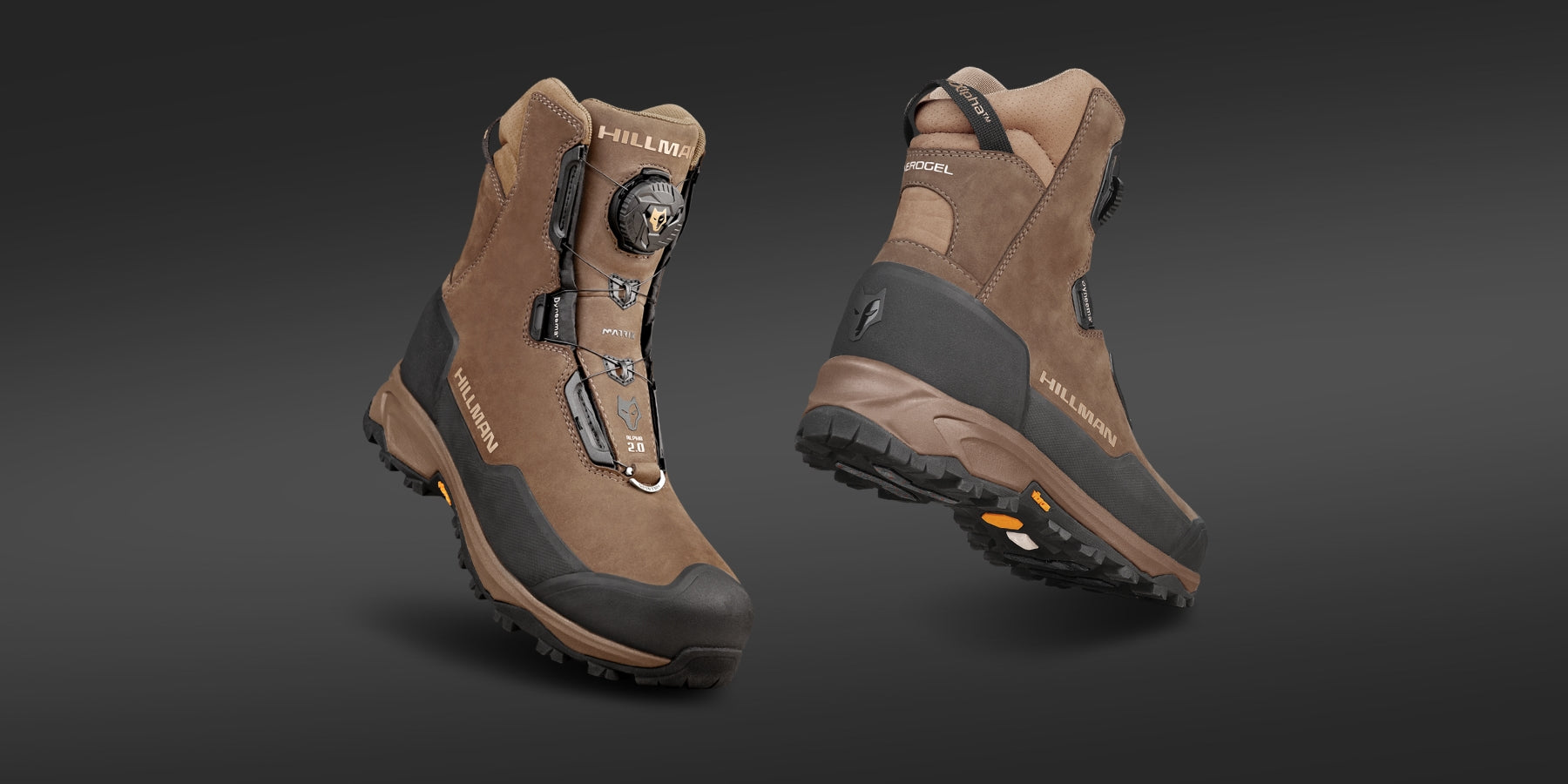 Two brown hiking boots are displayed against a dark background. One boot is upright, showcasing the front and side with a visible logo, lace system, and black toe guard. The other boot is positioned to show the heel and rugged sole pattern.