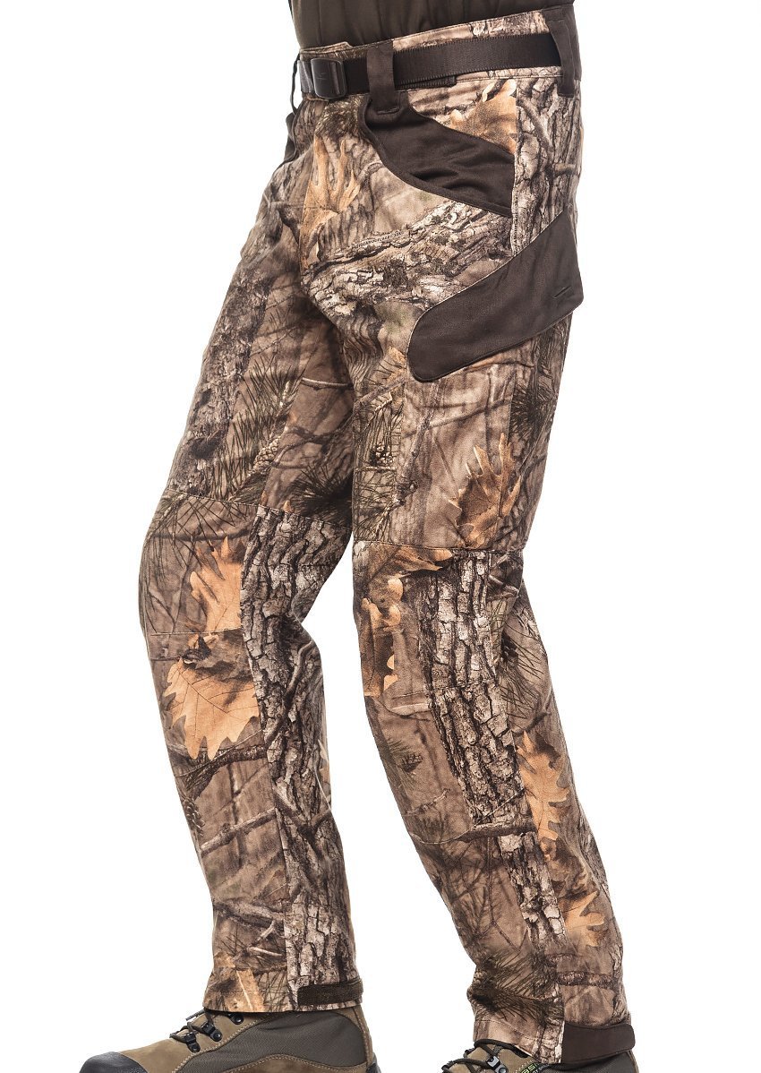 A person dressed in XPR Ultralight Climatronic Hunting Pants by Hillman® wears camouflage-patterned pants featuring brown pocket and knee patches. Made from cotton suede, the outfit includes a belt and hiking boots, showcasing a tree bark and leaf woodland pattern for authentic outdoor use.