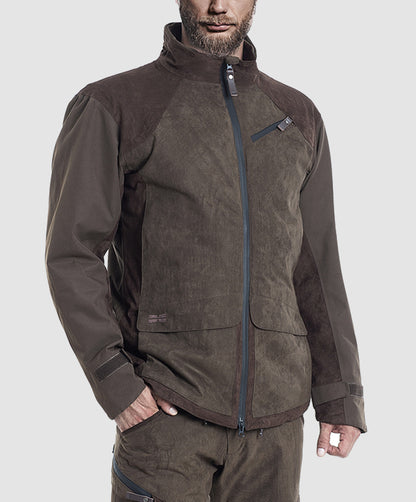 A man wearing the Hillman® PRE-ORDER Fusion Hunting Jacket, a durable brown outdoor piece with a high collar, zippered front, and chest pocket, along with matching pants, stands against a plain light gray background.