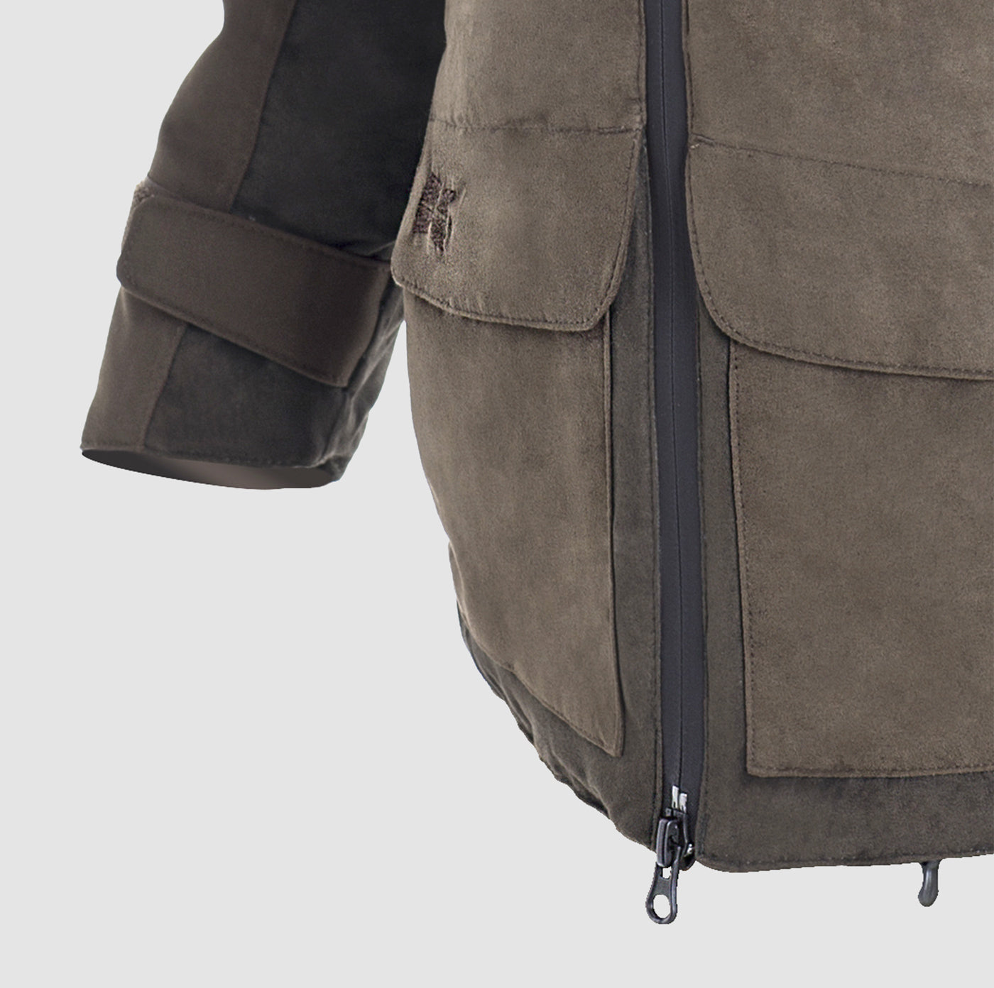 Close-up of the Hillman® PRE-ORDER Fusion Hunting Jacket in brown suede, showing a front zipper, large flap pocket, and sleeve with cuff strap. The jacket is set against a plain light gray background.