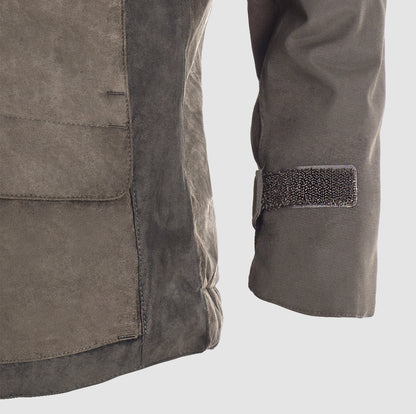 A close-up of the lower left side and sleeve of the Hillman® PRE-ORDER Fusion Hunting Jacket, featuring a large front pocket, seam details, and a Velcro strap on the cuff in durable brown suede.