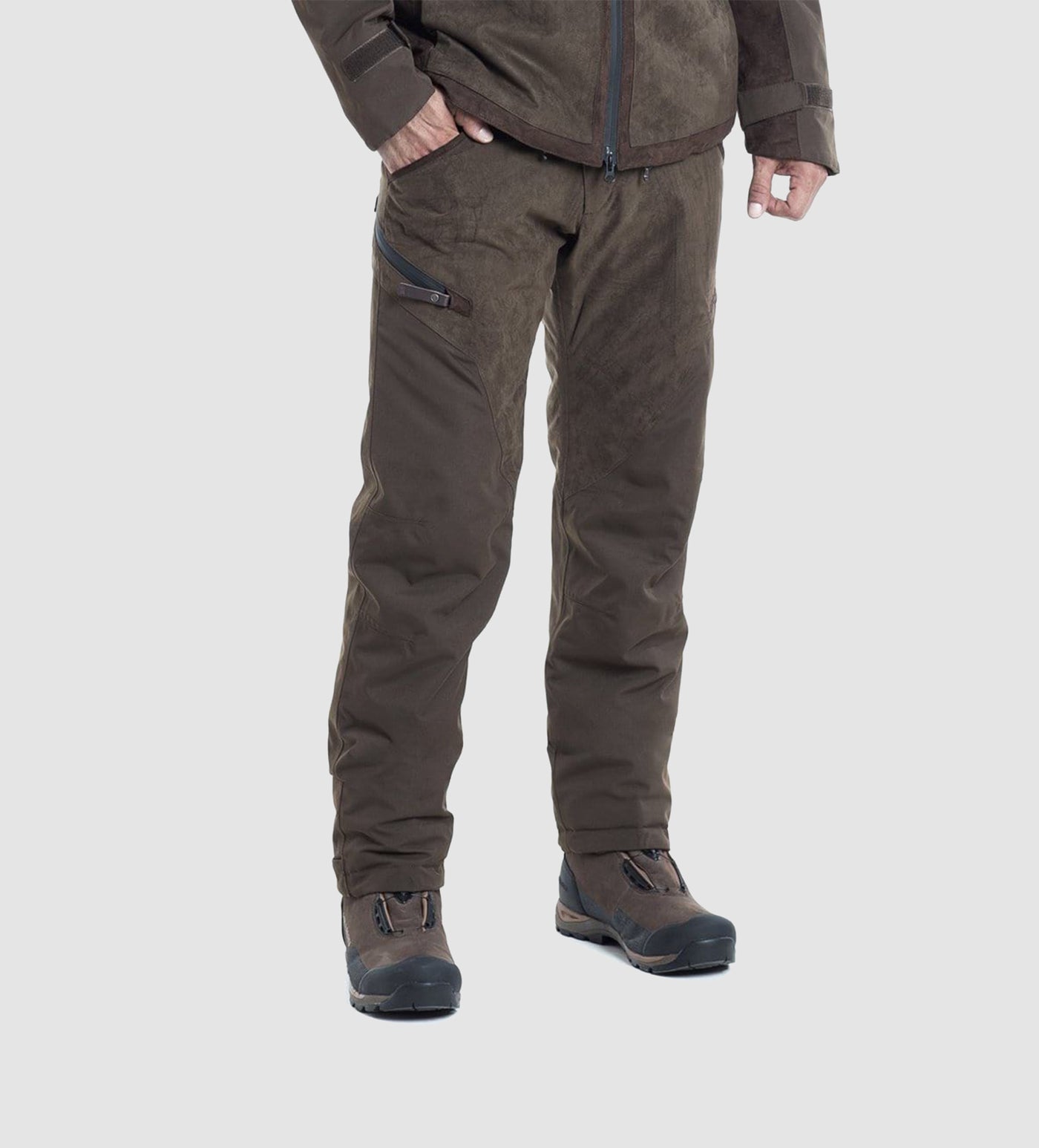 A person models the lower half of Hillman® PRE-ORDER Fusion Waterproof Hunting Pants in dark brown, paired with a matching jacket and black hiking shoes against a light background.