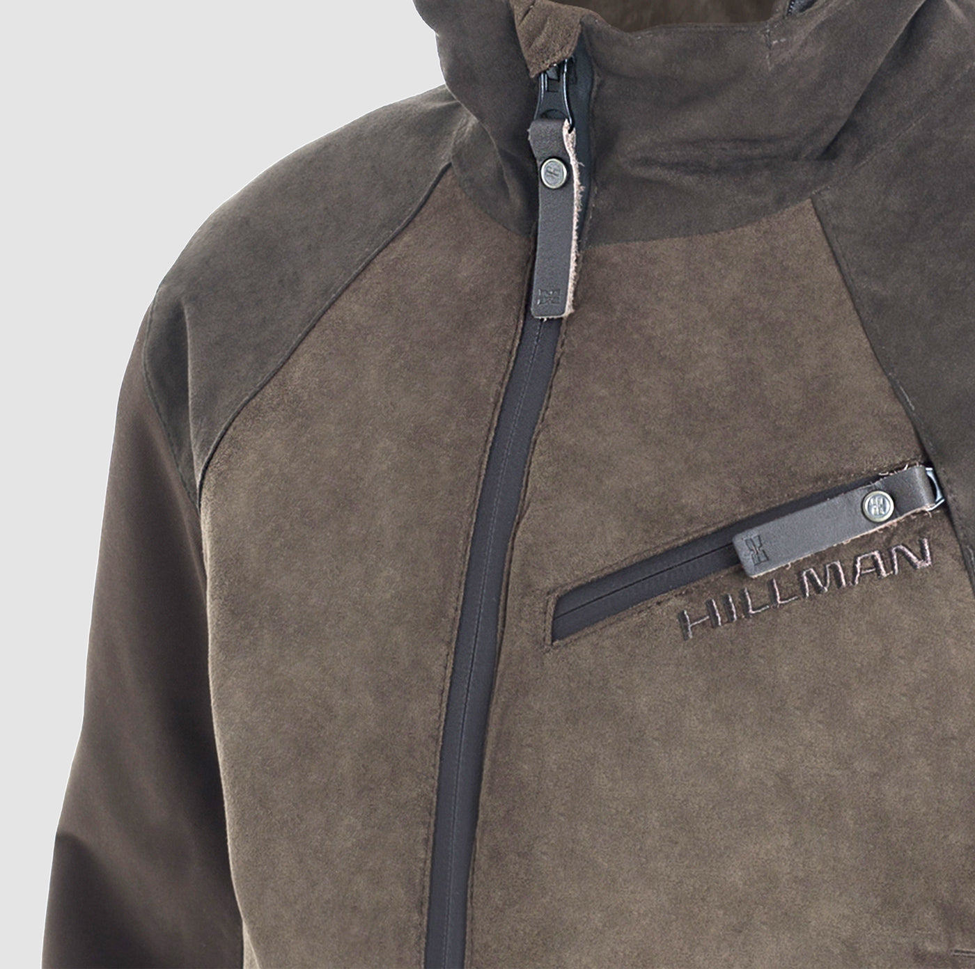 A close-up of the Hillman® PRE-ORDER Fusion Hunting Jacket, a brown and dark gray waterproof jacket with a vertical zipper, zippered chest pocket, and HILLMAN embroidered above the pocket.