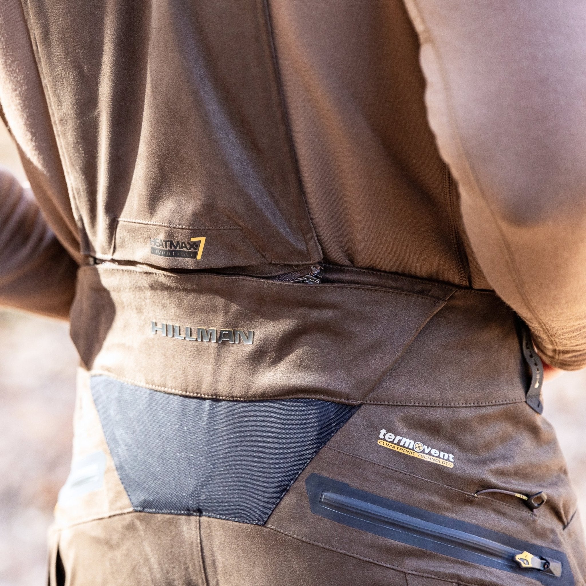 A close-up shows a person in HILLMAN GEAR Insulated Hunting Pants 6OL Cold Weather Waterproof Bibs, highlighting logos, zippers, Matrix Insulation, and stitching on the back.