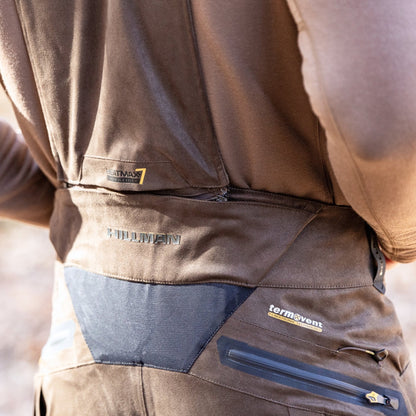 A close-up shows a person in HILLMAN GEAR Insulated Hunting Pants 6OL Cold Weather Waterproof Bibs, highlighting logos, zippers, Matrix Insulation, and stitching on the back.