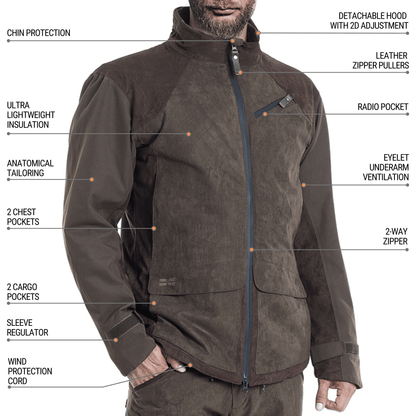 A man wears the Hillman® Waterproof Insulated Hunting Jacket | Fusion in brown, featuring chin protection, detachable hood, leather zipper pullers, multiple pockets, anatomical tailoring, insulation, sleeve regulator, and a wind protection cord.