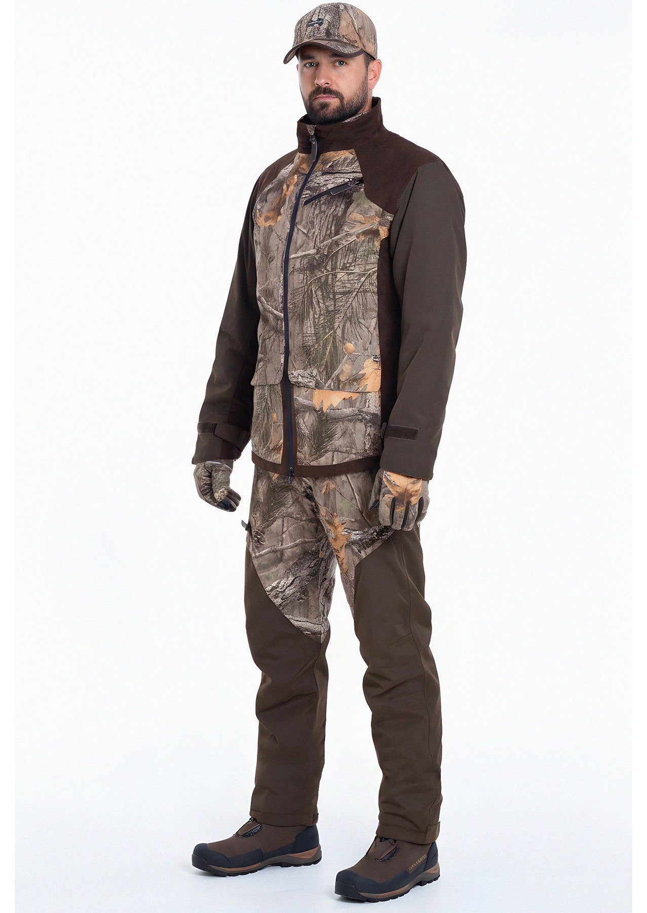 A man faces forward wearing the Hillman® Waterproof Insulated Hunting Jacket | Fusion, with matching camo pants and cap—perfect for cold weather hunts. He wears brown boots and stands against a plain white background with a neutral expression.