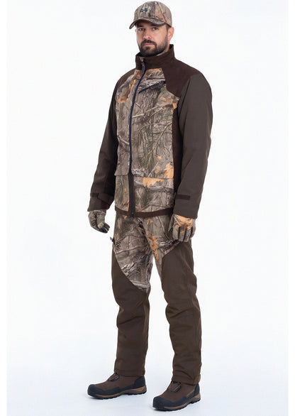 A man faces forward wearing the Hillman® Waterproof Insulated Hunting Jacket | Fusion, with matching camo pants and cap—perfect for cold weather hunts. He wears brown boots and stands against a plain white background with a neutral expression.