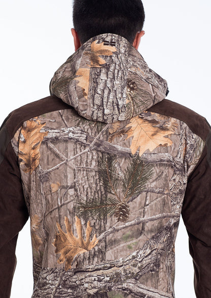 A person wears the Hillman® Waterproof Insulated Hunting Jacket | Fusion in a woodland camouflage pattern, facing away from the camera to showcase the back of this ideal cold weather hunting jacket.