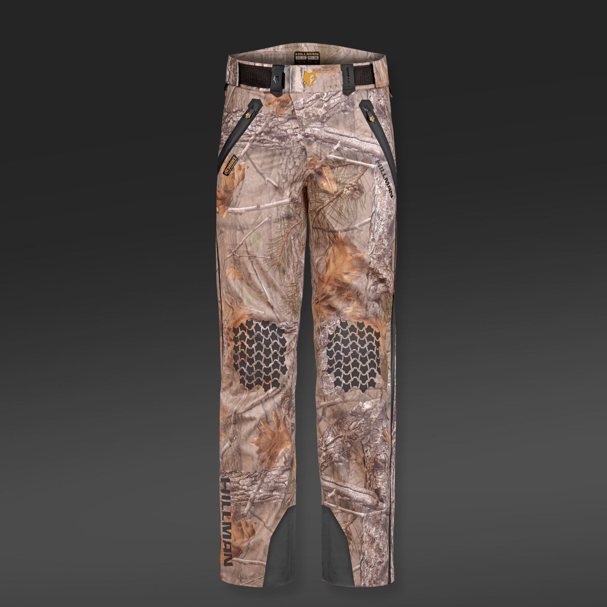 HILLMAN GEARs 5WL Waterproof Camo Hunting Pants feature a dark gray camouflage design with zipper pockets, knee hexagonal patterns, and branding near the lower left leg. Made from ultra-lightweight material with reinforced stitching, theyre perfect for rugged outdoor adventures.