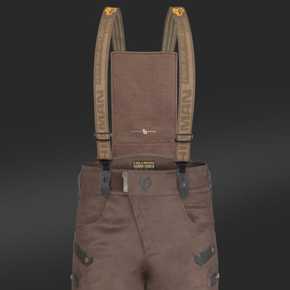 Close-up of HILLMAN GEAR Insulated Hunting Pants 6OL Cold Weather Waterproof Bibs featuring brown fabric, Matrix Insulation, dark reinforced patches, belt loops, multiple pockets, and adjustable branded suspenders. Solid black background.