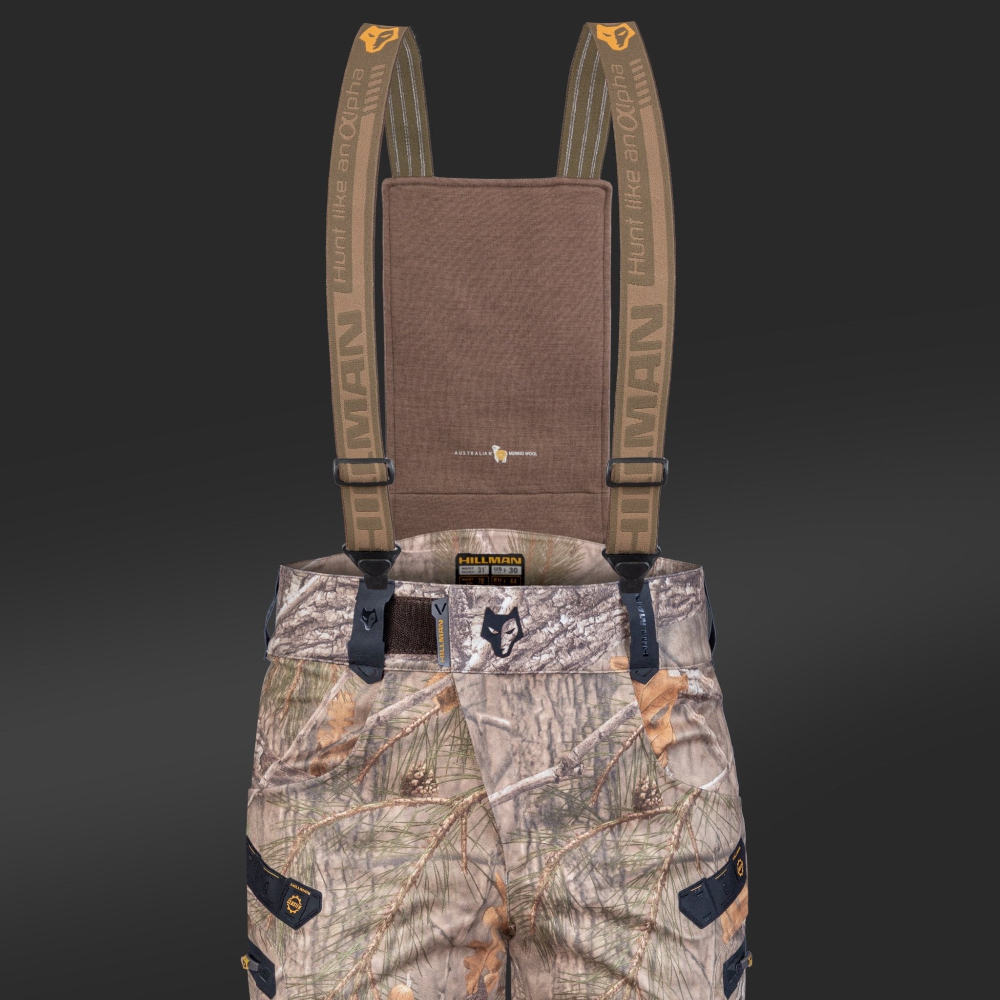 A pair of HILLMAN GEAR Insulated Hunting Pants 6OL Cold Weather Waterproof Bibs with tan HUMAN suspenders, black buckles, Matrix Insulation, and a brown chest panel are shown against a dark background.
