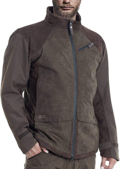 A person wears the Hillman® Fusion Hunting Jacket in dark green and brown, showing a high collar, zippered pockets, breathable membrane, front zipper, and adjustable cuffs. The bottom half of their face is visible.