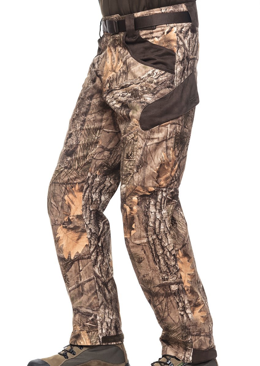 A person is wearing Hillman® XPR Ultralight Climatronic Hunting Pants with a leafy photocamouflage pattern in shades of brown and green, designed for silent movement, along with brown hiking boots. They are standing while their upper body remains out of view.